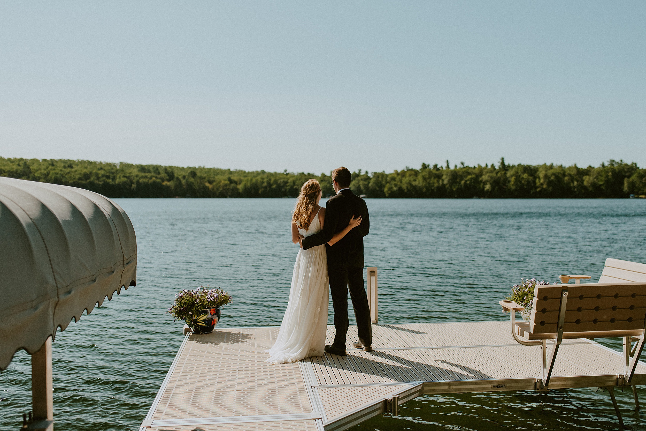 bride and groom standing on dock overlooking water in northern wisconsin