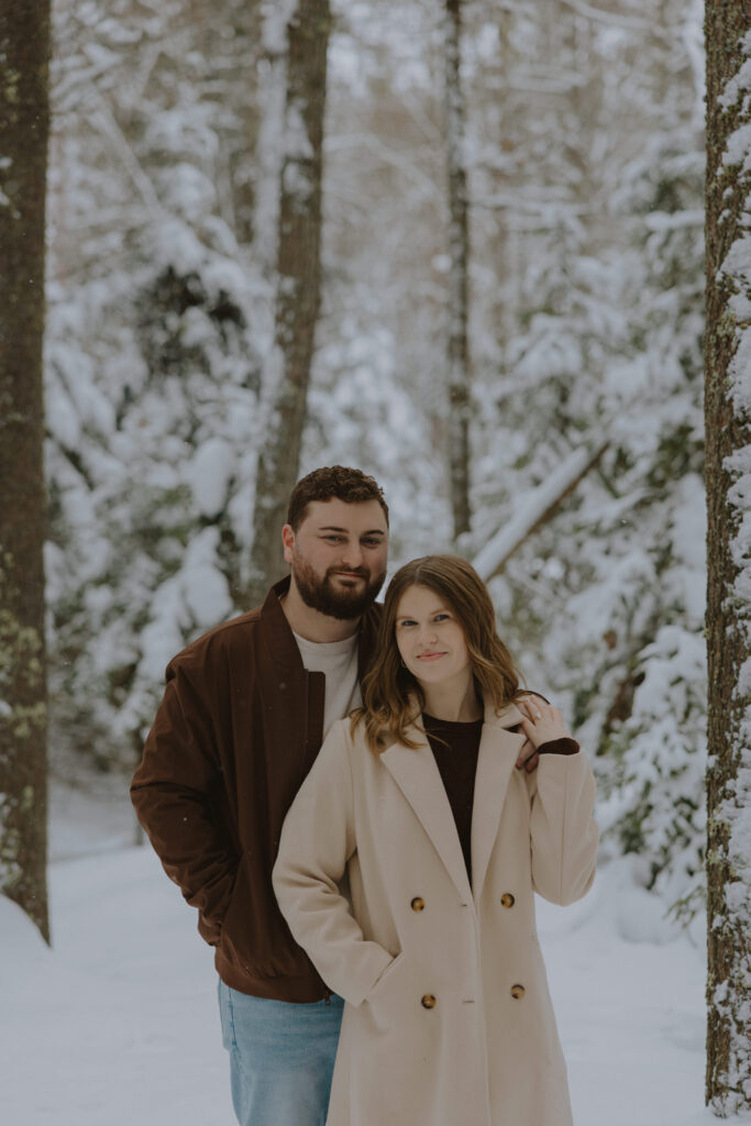 Couple standing together during a winter engagement session in a snowy Northern Wisconsin forest