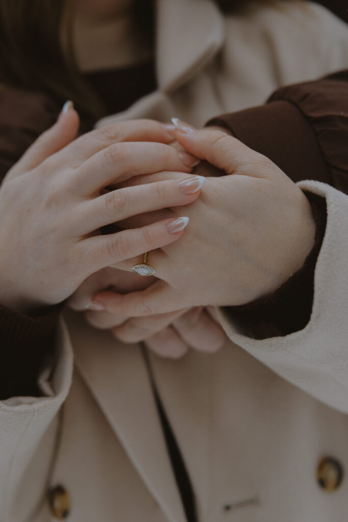 Close-up of an engagement ring as a couple holds hands during a winter engagement session in Northern Wisconsin