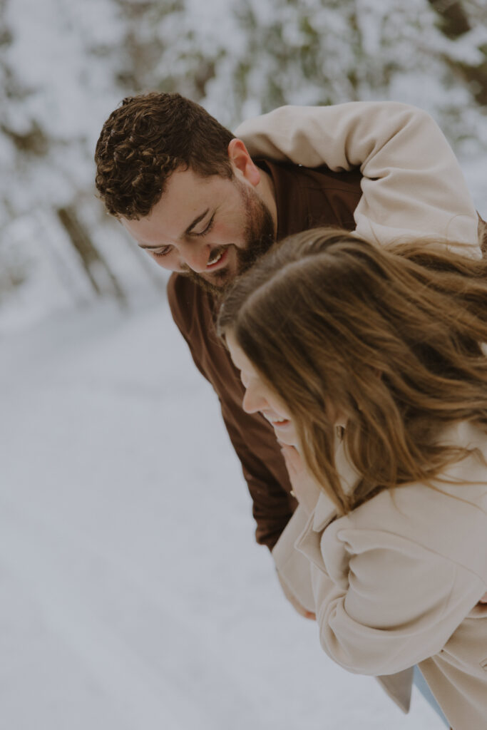 Candid winter engagement photo of a couple laughing together in the snow in Northern Wisconsin