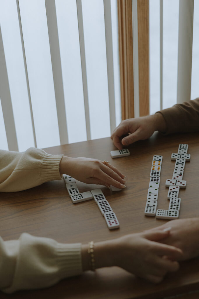 Close-up of hands playing dominos during a cozy cabin engagement session in Northern Wisconsin
